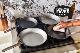 Hand wiping best carbon steel skillets displayed on stovetop