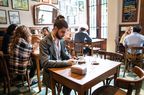 A person sits alone waiting for their party in a restaurant