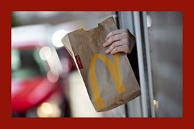 An employee hands a customer order at the drive-thru of a McDonald's restaurant.