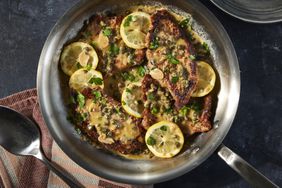 Top down view of veal piccata with lemons and capers in a pan.