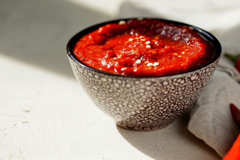 Traditional homemade rose harissa-hot chili pepper sauce paste with garlic and olive oil in small bowl