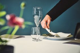 A server sets a place setting on a table at Osteria Francescana 